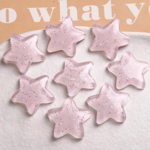 Close-up of pink translucent resin stars with silver glitter inside on a ceramic plate