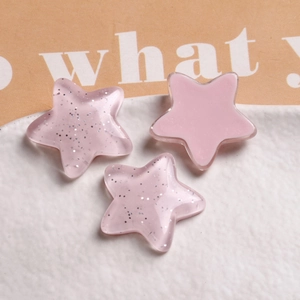Close-up of pink star-shaped resin charms with glitter on a white ceramic plate