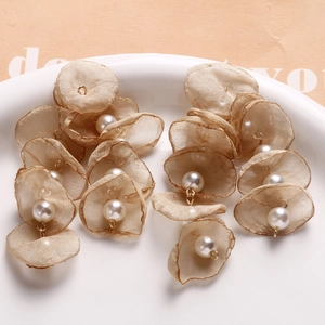 Close-up of handmade champagne organza petal charms with pearl accents and metal loops