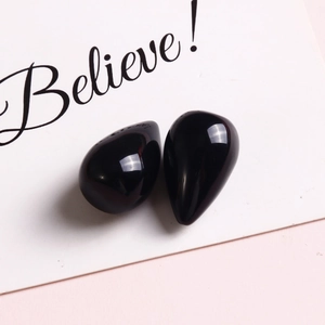 Close-up of elegant polished black teardrop charms with mirror-like finish for jewelry making