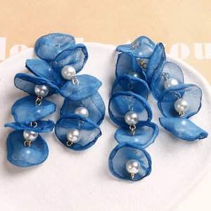 Handmade mesh flower petal earrings with white pearls on a minimalist ceramic plate