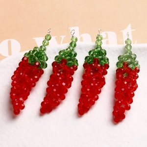 Macro shot of four handmade glass chili pepper charms with vibrant red and green beads