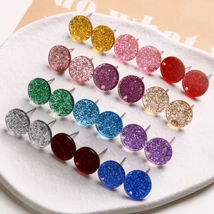 Macro view of twelve pairs of colorful round glitter resin earrings on ceramic tray