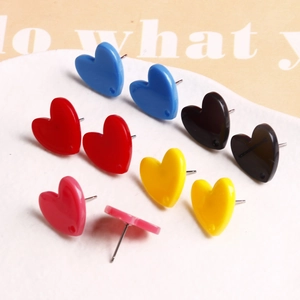 Gros plan de boucles d'oreilles cœur en acrylique de couleurs variées sur plat blanc