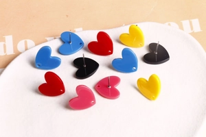 Vue détaillée de boucles d'oreilles cœur en acrylique coloré sur un plateau en céramique