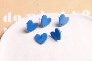 Détail de cinq boucles d'oreilles cœur bleu en acrylique sur une assiette blanche