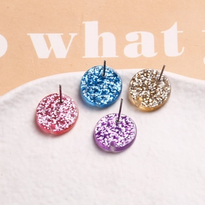 Macro shot of colorful resin round stud earrings with glitter foil inlay and metal pins