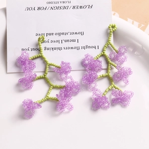 Détail de boucles d'oreilles en perles de verre faites main lilas et vert