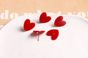 Gros plan de cinq boucles d'oreilles cœur en acrylique rouge sur un plateau en céramique