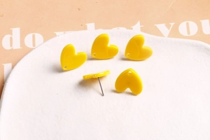 Détails de boucles d'oreilles en cœur acrylique jaune vif sur plat en céramique