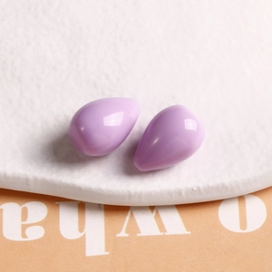 Close-up of lavender purple teardrop resin earring charms on a white stone tray
