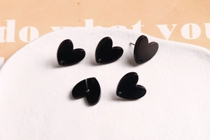 Gros plan de boucles d'oreilles cœur noires en acrylique sur un plateau en céramique