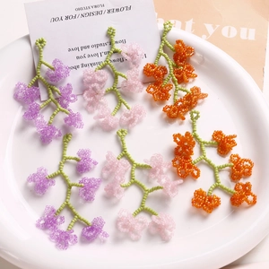 Gros plan de grappes de fleurs en perles tissées à la main dans les tons violet, rose et orange