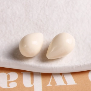 Macro shot of two cream-colored resin teardrop pendants for DIY jewelry making