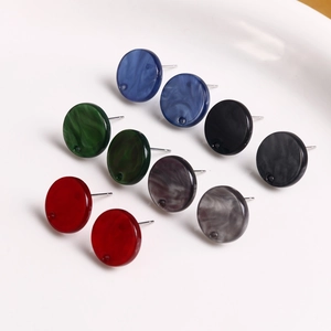 Buntes Set aus runden Acryl-Ohrsteckern in fünf eleganten Farben auf einem Keramiktablett