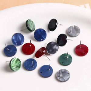 Bunte runde Acryl-Ohrstecker und DIY-Schmuckzubehör auf einer weißen Keramikplatte