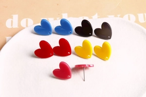 Détails macro de boucles d'oreilles en cœur acrylique coloré avec petits trous décoratifs