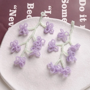 Vue détaillée de boucles d'oreilles florales en perles violettes et vertes faites à la main