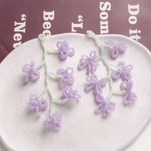 Boucles d'oreilles fleurs perlées à la main en lavande et vert sur un plat céramique