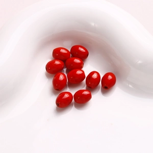 Primer plano de cuentas de turquesa roja ovaladas para joyería DIY sobre cerámica blanca