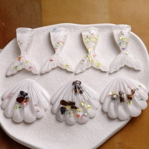 Macro view of transparent resin fish tails and shells with holographic glitter details