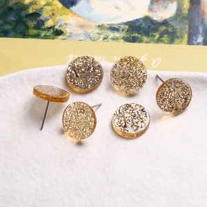 Macro shot of circular amber resin earrings with gold and silver glitter foil particles