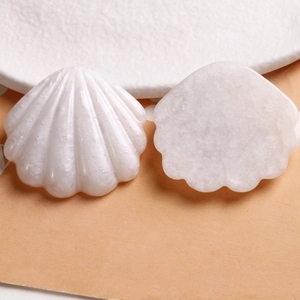 Détail macro d'outils guasha en résine blanche en forme de coquillage aux surfaces lisses
