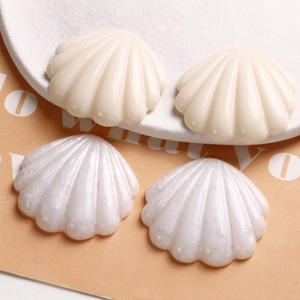 Vue macro d'accessoires en résine en forme de coquille en blanc crème et nacré