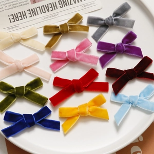 Macro shot of assorted colorful velvet bow hair clips displayed on a white ceramic plate