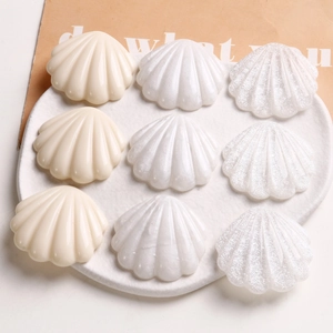 Vue détaillée de neuf accessoires de coquillages en résine colorés dans un plat en céramique