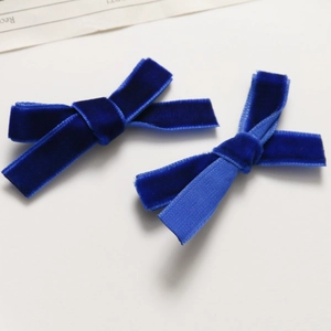 Detail view of deep blue velvet ribbon bow hair clips showing soft fabric texture