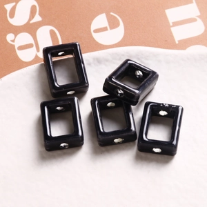 Gros plan de cinq perles rectangulaires creuses en céramique noire pour bijoux DIY