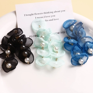 Macro shot of layered organza mesh flower earrings with central white pearls in various colors