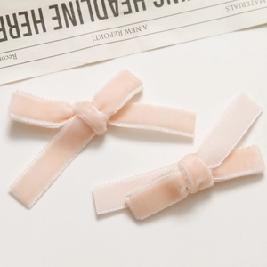 Close-up of a pair of light pink velvet bow hair clips with soft textured ribbon detail