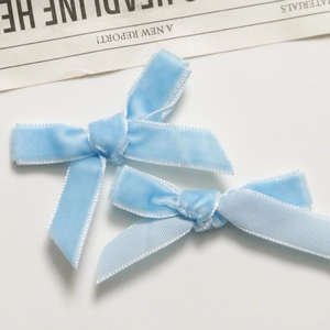 Close-up of light blue velvet bow hair clips on a clean white background with a newspaper