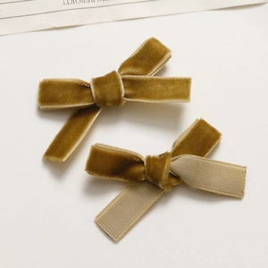 Close-up of mustard yellow velvet bow hair clips with ribbed ribbon backing and texture