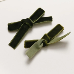 Detail view of dark green velvet bow hair clips with contrasting light green ribbon lining
