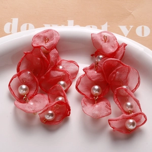 Detail of red mesh petal earrings with white pearls on a white ceramic plate