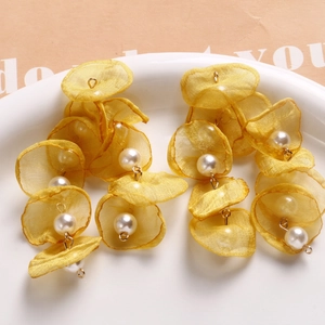 Macro shot of long floral earrings featuring yellow organza petals and white pearls