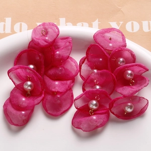 Detailed macro of fuchsia organza petal earrings featuring white pearls and gold accents
