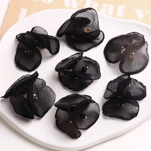 Primer plano de siete flores de malla negra hechas a mano con detalles de cuentas de cristal