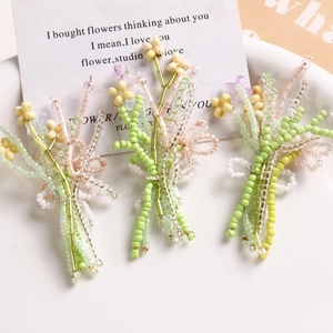 Close-up of three handmade bead flower bouquets in green, pink and purple colors