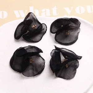 Detalle de flores de malla negra hechas a mano con cuentas sobre un plato blanco