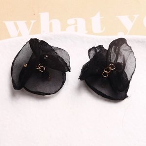 Detalle de pendientes de pétalos de malla negra con anillo de metal dorado y perlas