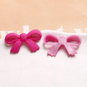 Vue macro de breloques nœuds en acrylique mat montrant la texture rose pour bijoux DIY