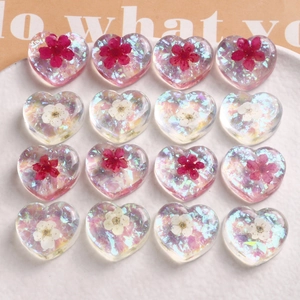 Macro detail of 16 heart-shaped resin charms with embedded dried flowers and glitter