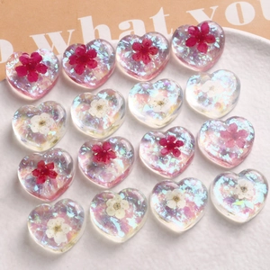 Macro shot of colorful resin heart charms with dried flowers and shimmering sequins
