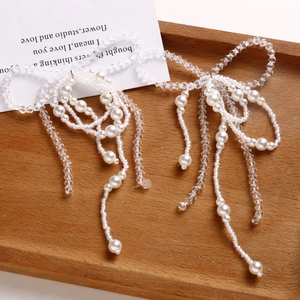Detailed view of handmade crystal bow accessories with elegant pearl tassels on a wood tray