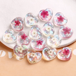 Colorful resin heart charms with dried flowers and iridescent foils in a white dish