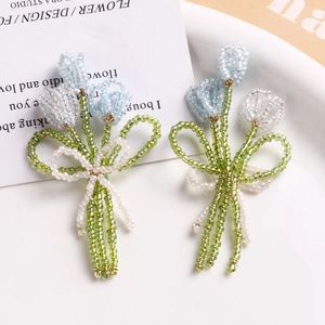 Détail d'un pendentif bouquet de tulipes perlé à la main avec un nœud blanc